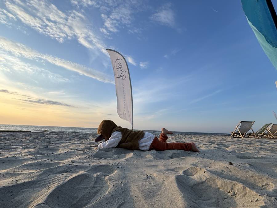 Kind im Sand vor der Bude bei Abendlicht